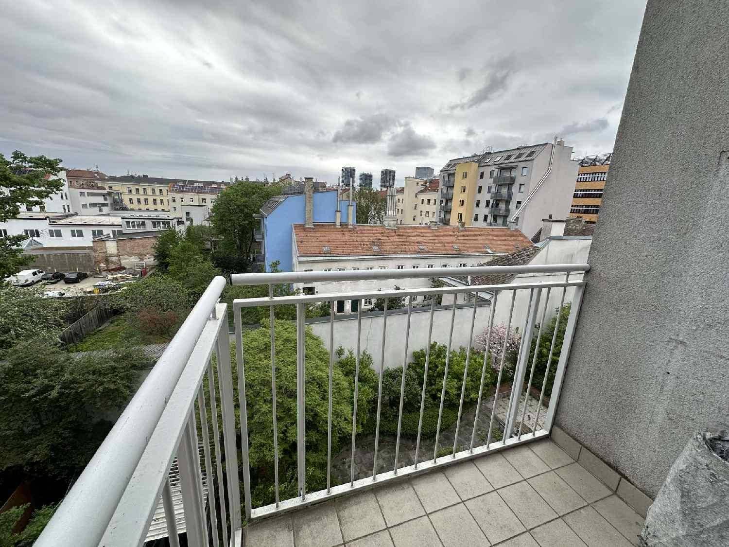 Balkon mit Fliesenboden und Blick auf die umliegende Stadtbebauung und grüne Hinterhöfe.