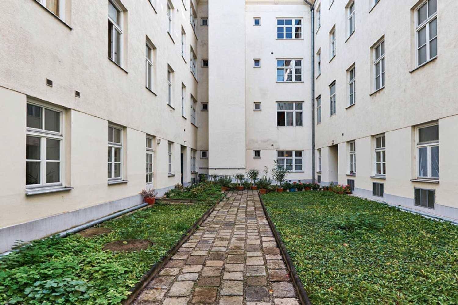 Grüner Innenhof mit gepflastertem Weg und üppiger Bepflanzung, umgeben von Wohngebäuden.