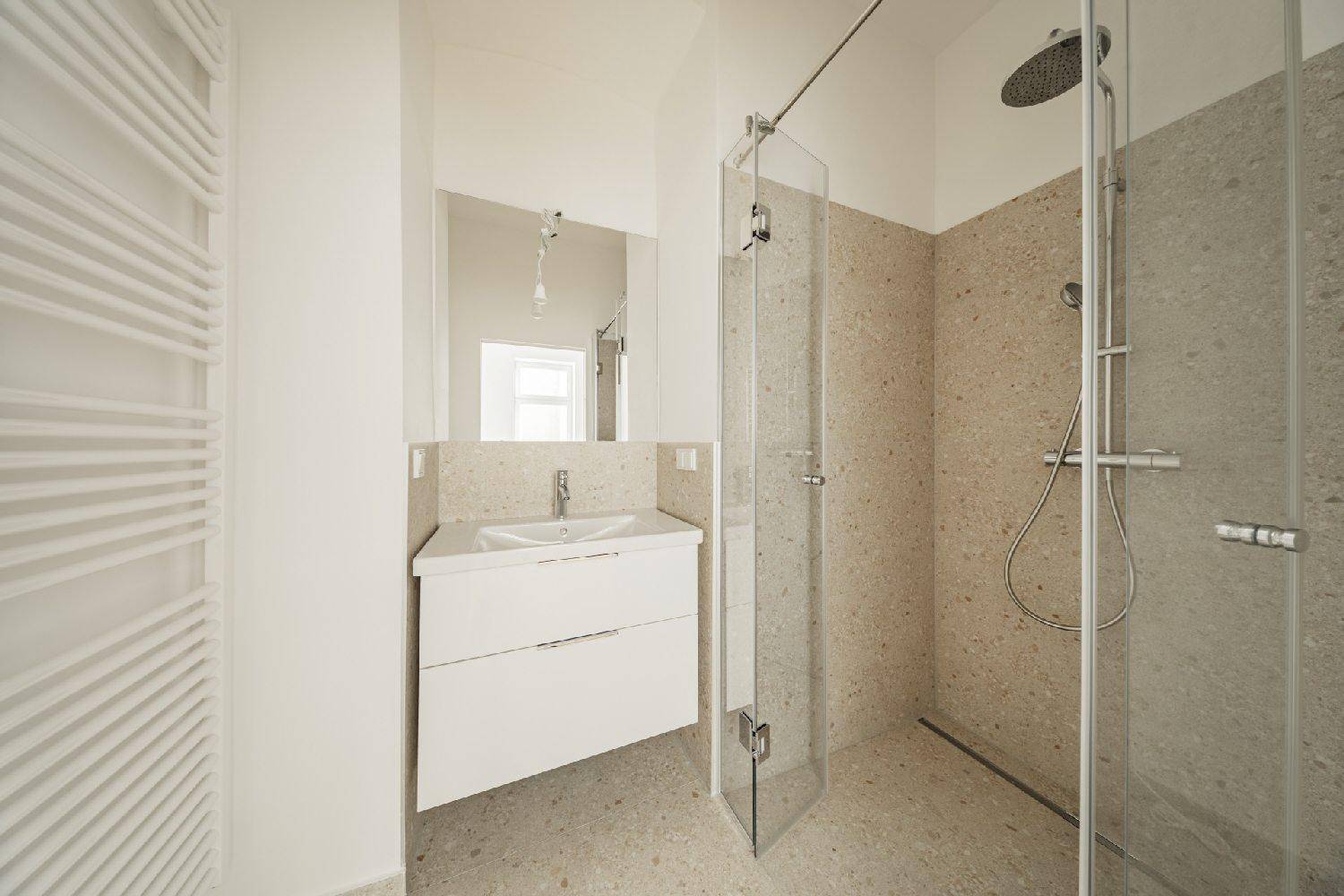 Modernes Badezimmer mit ebenerdiger Dusche, elegantem Waschtisch und beheiztem Handtuchhalter.