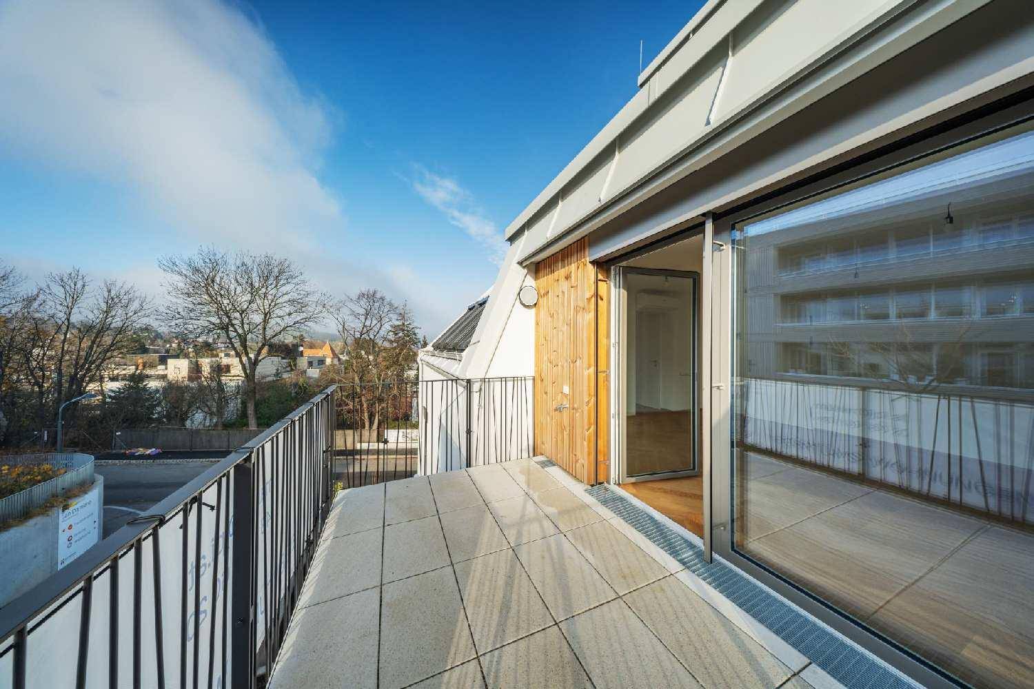 Geräumiger Balkon mit Fliesenboden und Blick auf die Umgebung und Bäume.