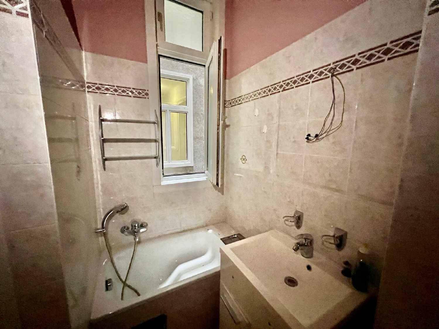 Kleines Badezimmer mit Badewanne, Waschbecken und Fliesen in Pastellfarben.