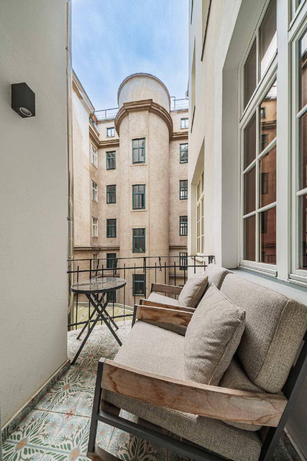 Kleiner Balkon mit Sitzgelegenheiten und Blick auf den Innenhof eines historischen Gebäudes.