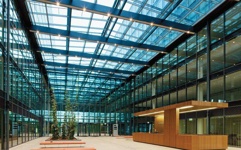 Helle und offene Lobby mit Glasdach, Rezeption und modernen Designelementen.