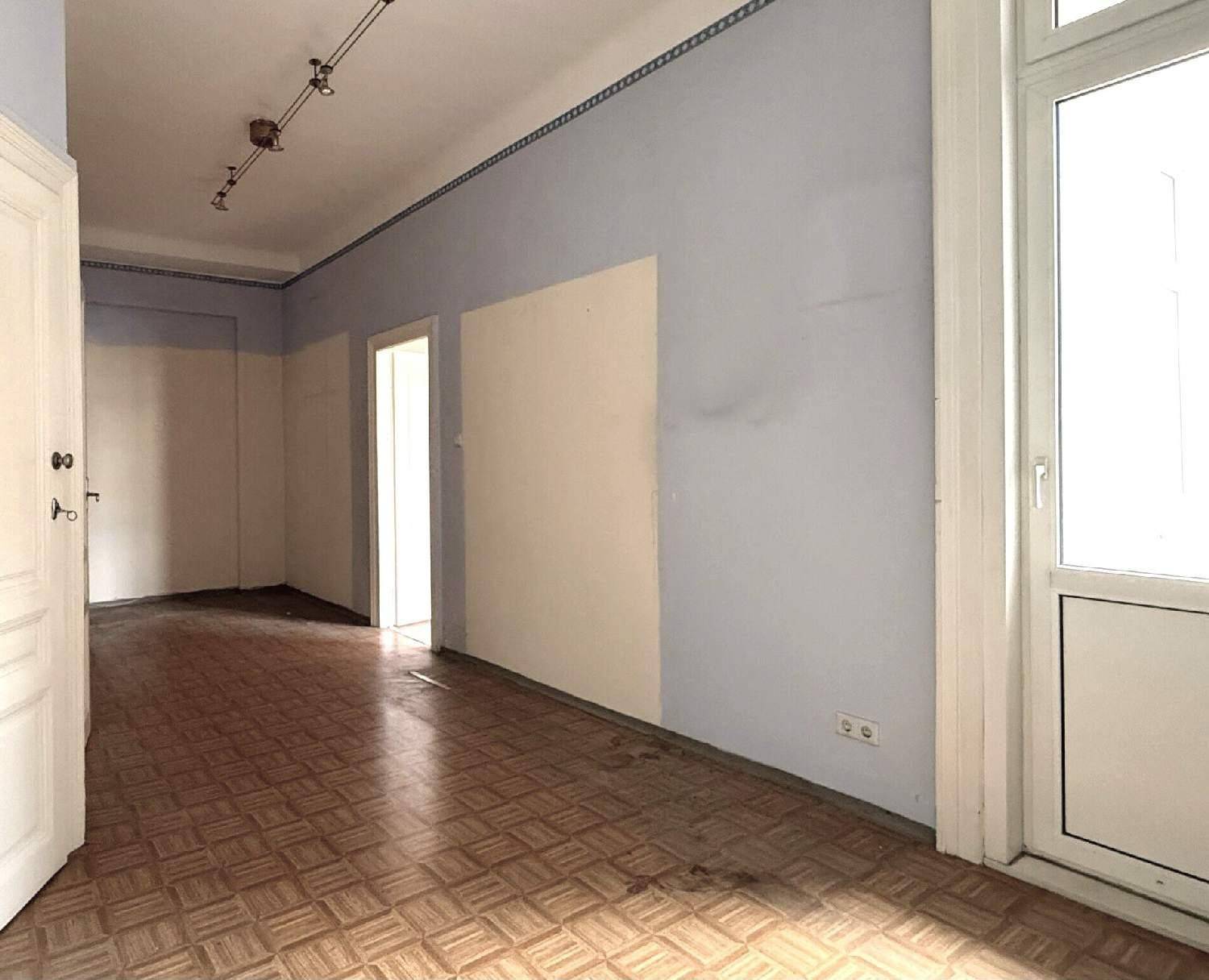 Heller Flur mit Laminatboden, blauen und beigen Wänden, mit Zugang zu einem Balkon.