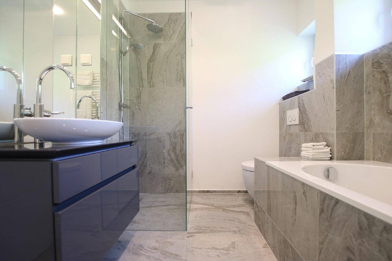 Luxuriöses Badezimmer mit Badewanne, begehbarer Dusche und modernen Marmorfliesen.