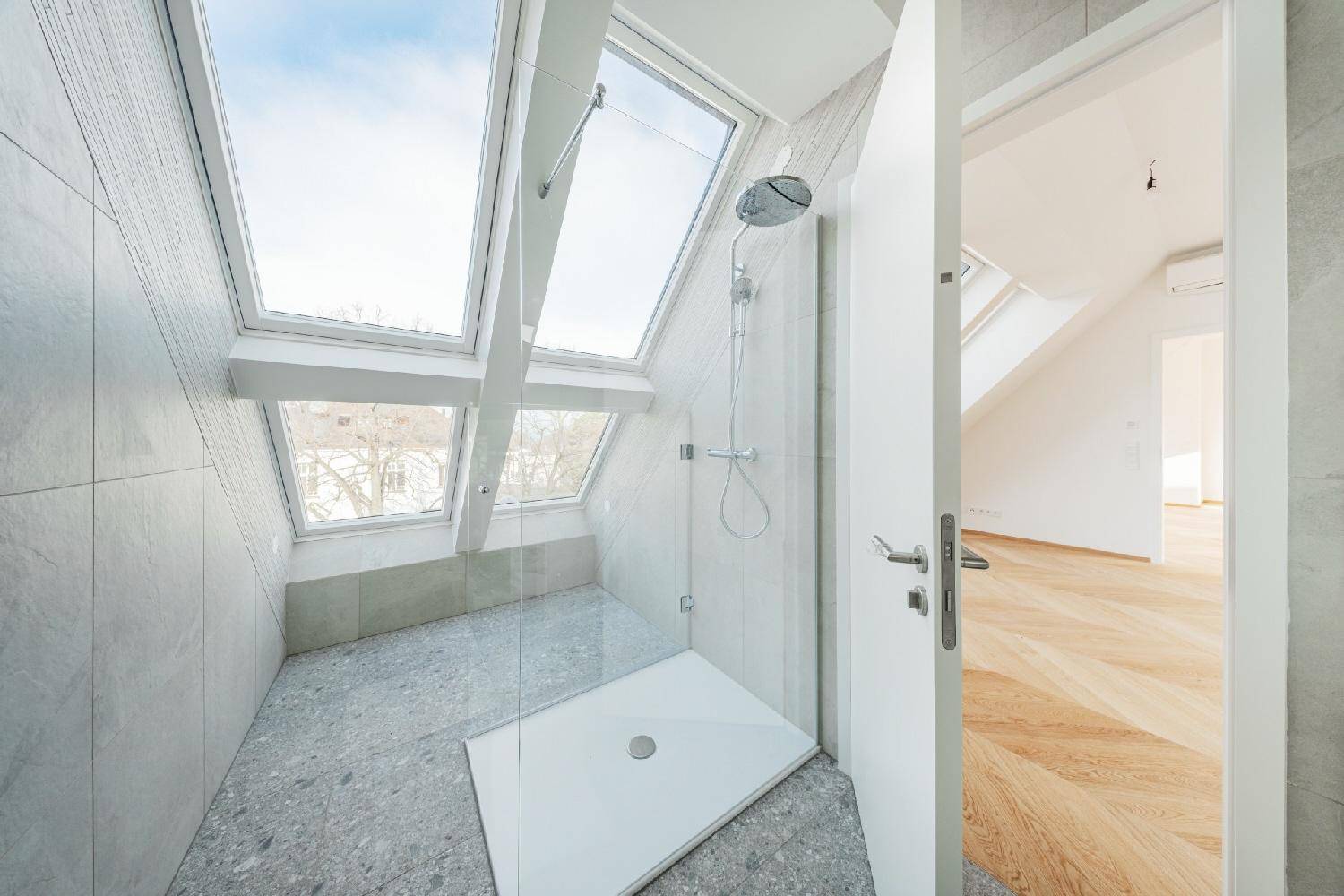 Helles Dachgeschoss-Badezimmer mit moderner Dusche und großen Dachfenstern.
