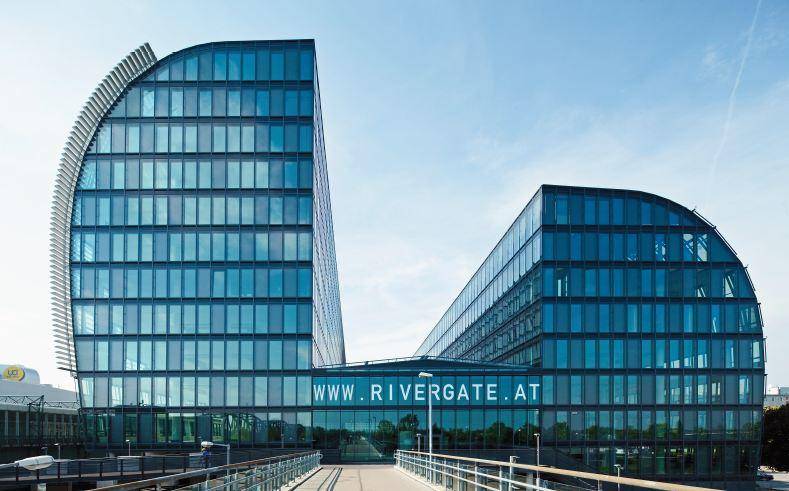 Beeindruckendes, modernes Bürogebäude mit geschwungener Glasfassade unter klarem blauem Himmel.