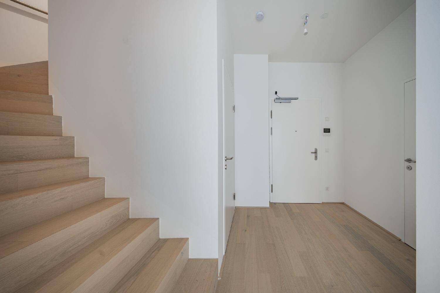 Heller Eingangsbereich mit moderner Holztreppe und Zugang zur oberen Etage des Hauses.