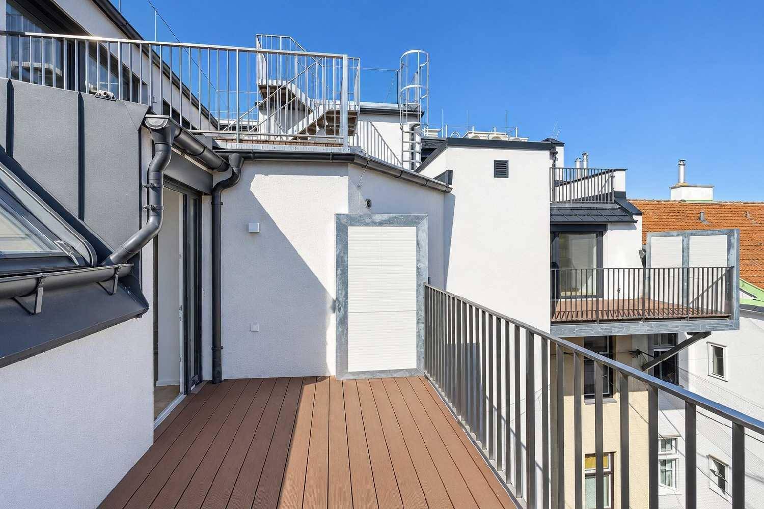 Geräumige Dachterrasse mit Metallgeländer und Zugang zu weiteren Ebenen.
