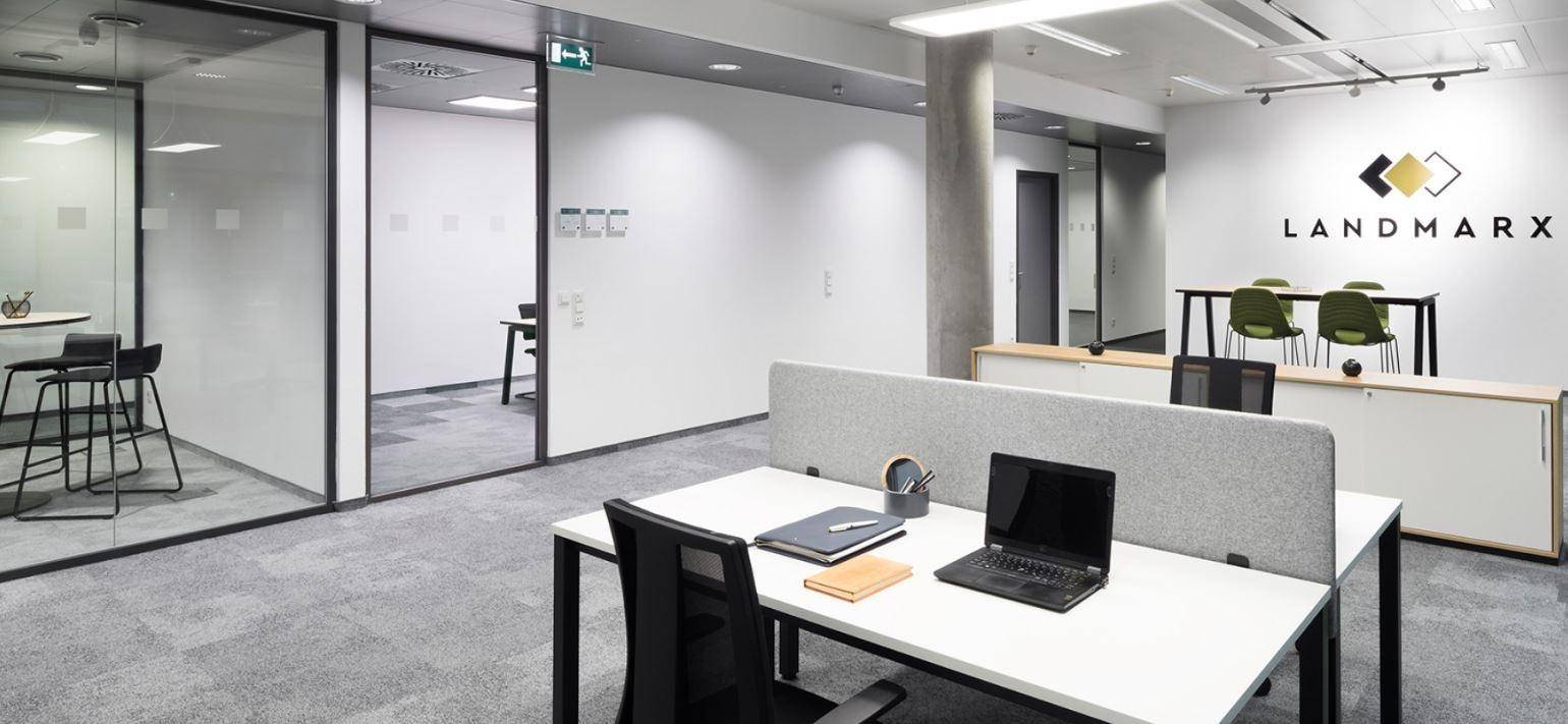 Heller und geräumiger Bürobereich mit mehreren Arbeitsplätzen und Glaswänden.