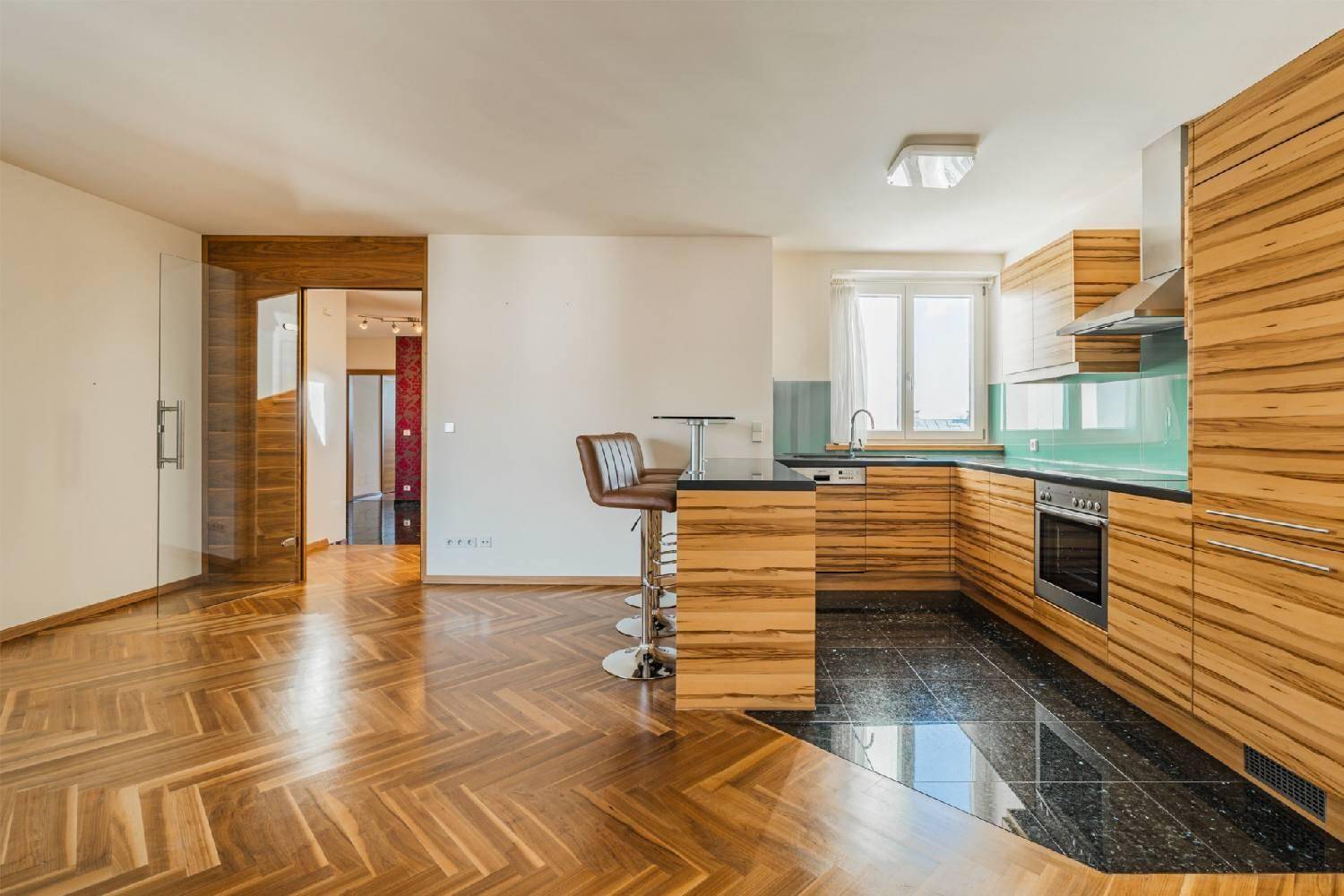 Moderne Küche mit Holzfronten, dunkler Arbeitsplatte und integrierter Frühstücksbar.