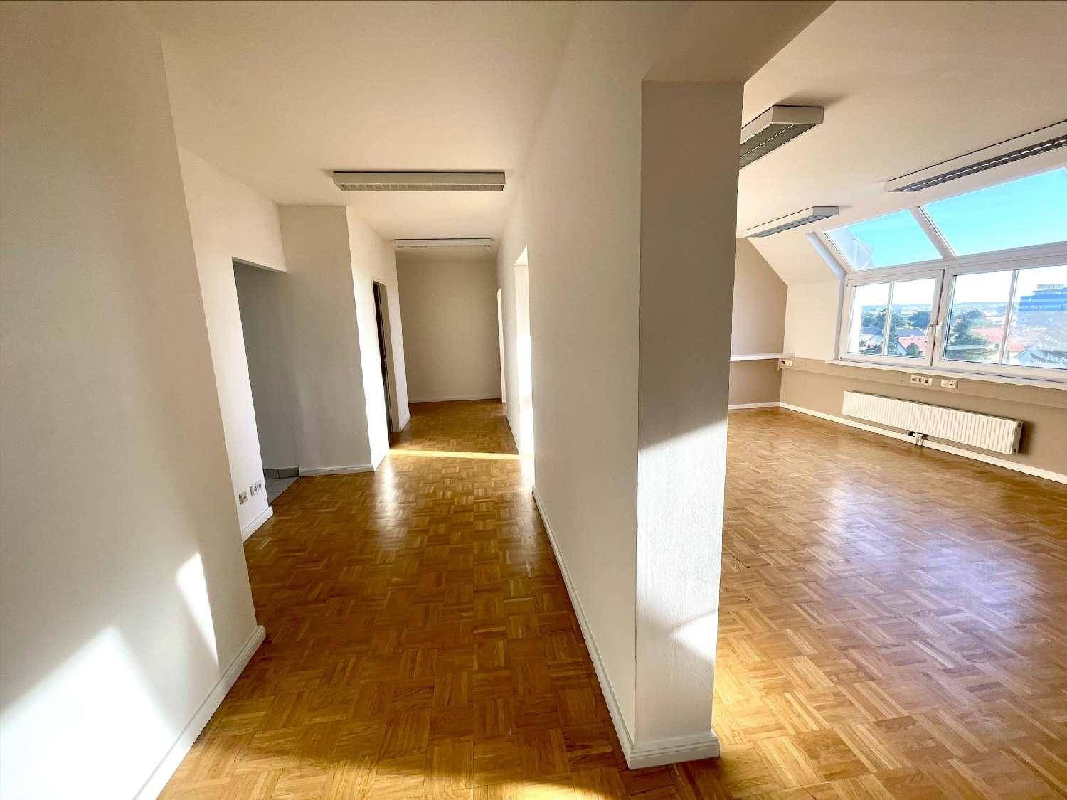 Heller Büroraum mit großen Fenstern, Parkettboden und einem langen Flur, der zu weiteren Räumen führt.