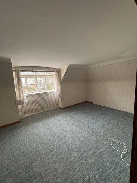 Schlafzimmer mit Teppichboden, großem Fenster und deutlichen Dachschrägen.