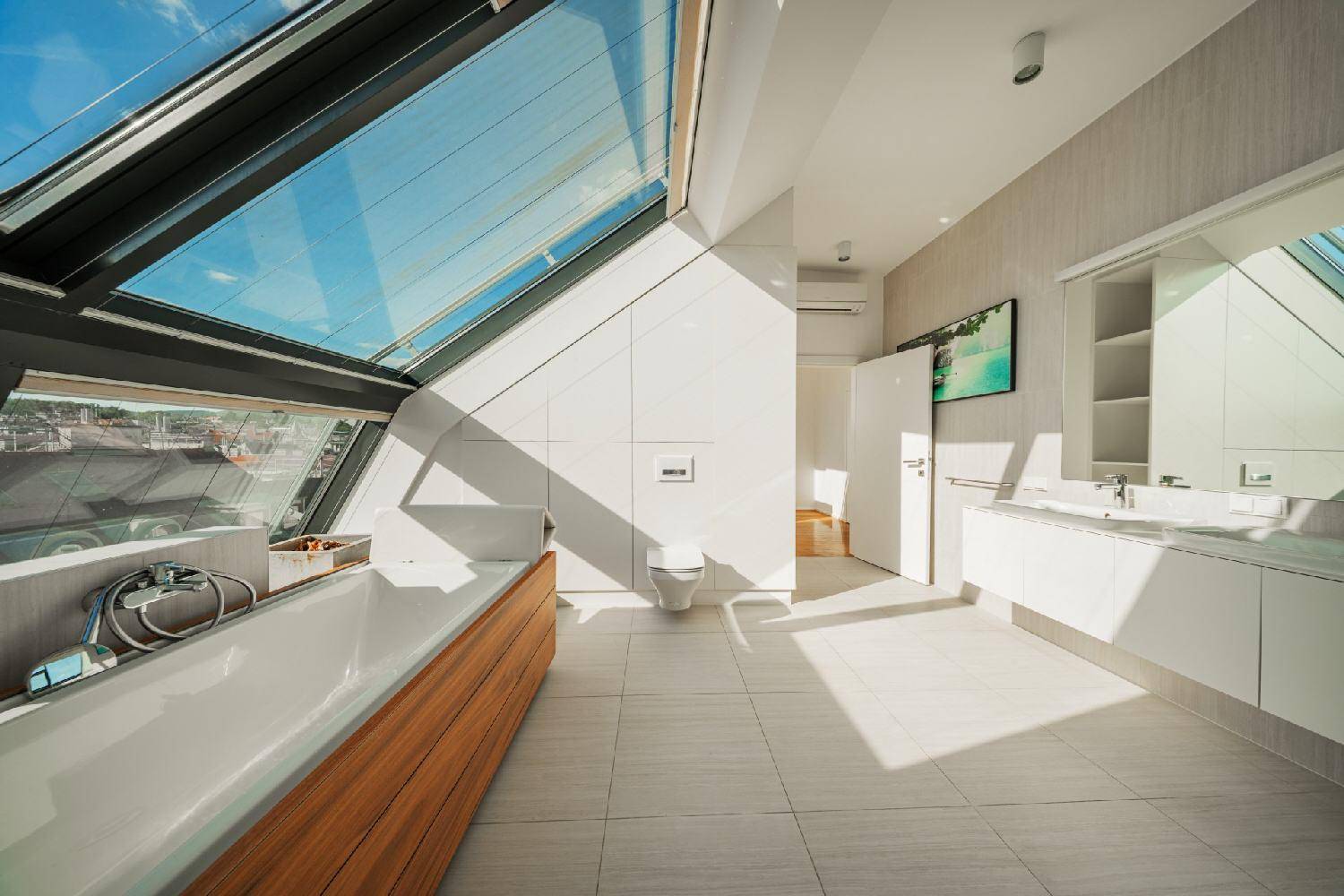 Großzügiges Badezimmer mit moderner Ausstattung, Doppelwaschbecken und viel Tageslicht durch die Dachfenster.