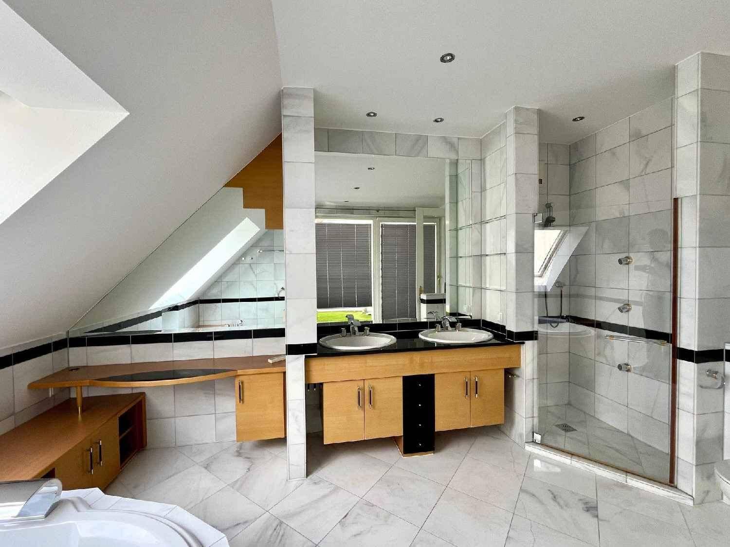Geräumiges Badezimmer mit Doppelwaschbecken, großer Dusche und Marmorfliesen unter der Dachschräge.