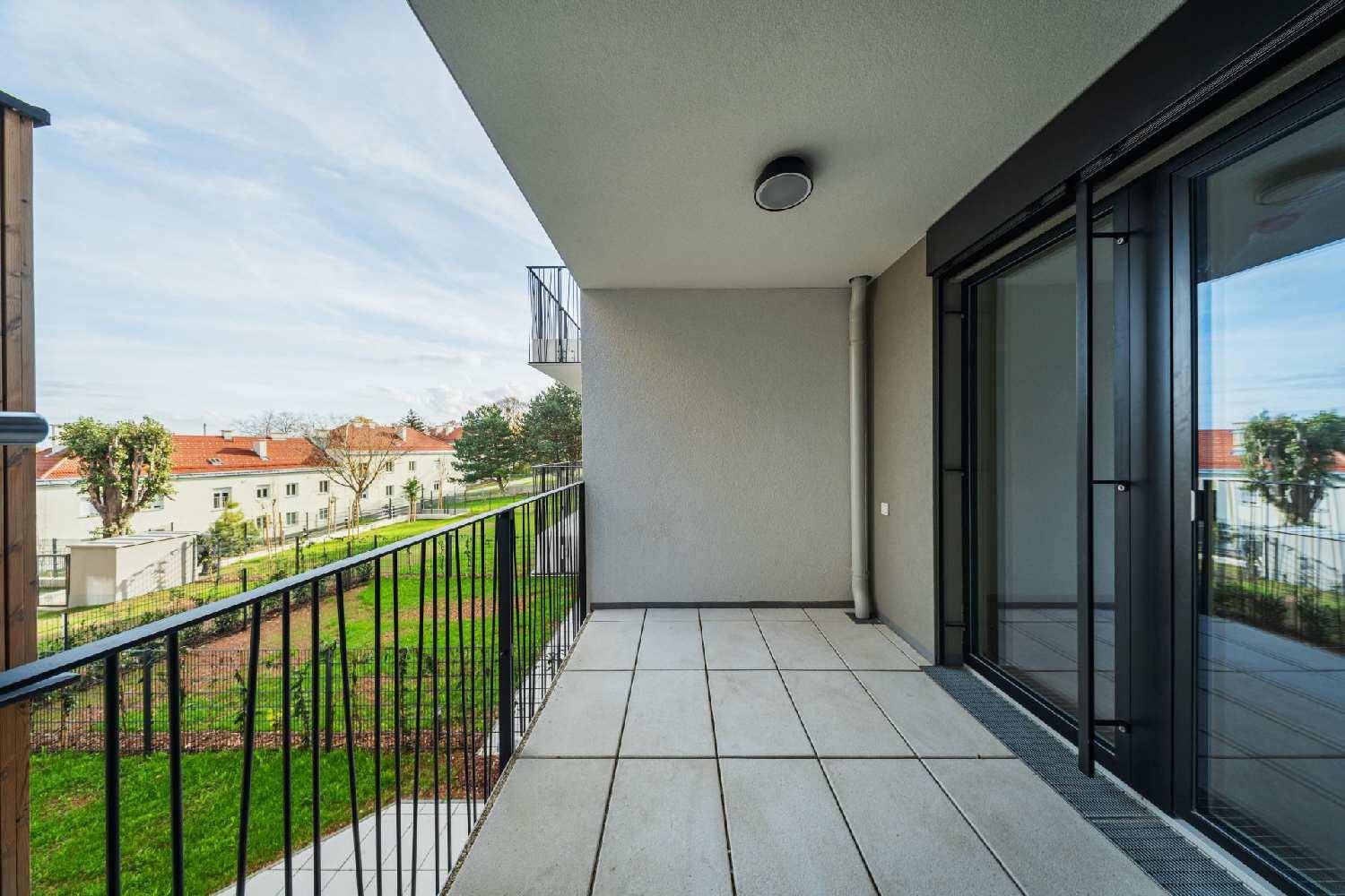 Geräumiger Balkon mit Fliesenboden und Blick auf die grüne Umgebung und Dächer.