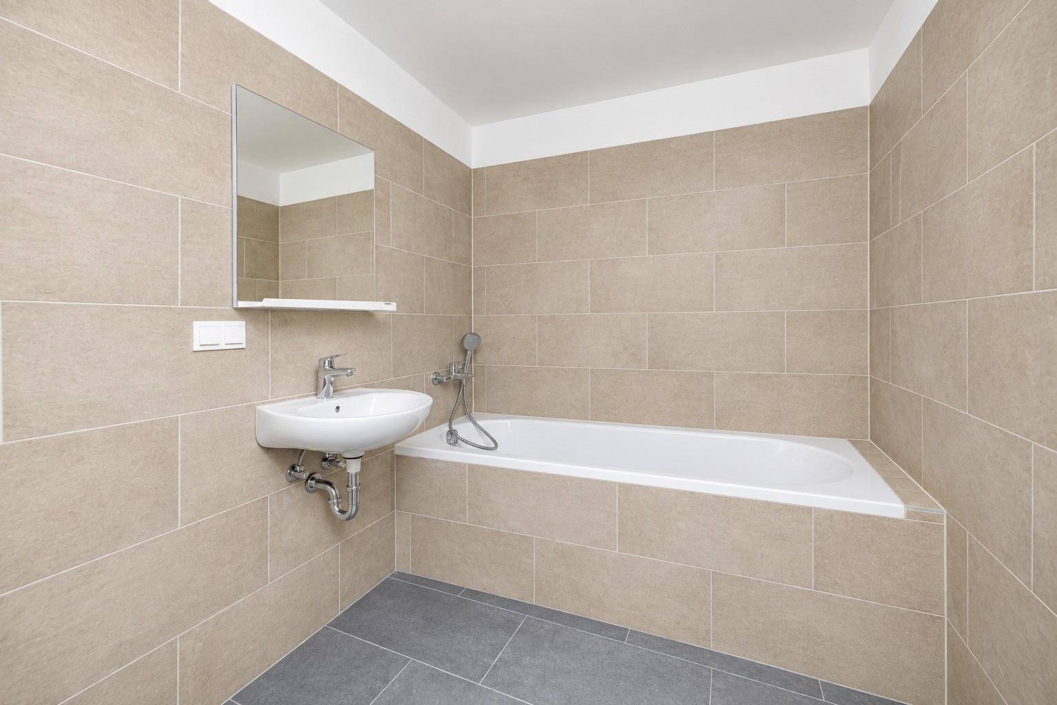 Modernes Badezimmer mit beigefarbenen Fliesen, Badewanne und Einzelwaschbecken.