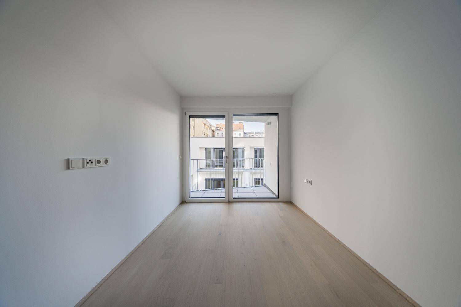 Helles Zimmer mit Parkettboden und französischem Balkon, ideal als Schlaf- oder Arbeitszimmer.
