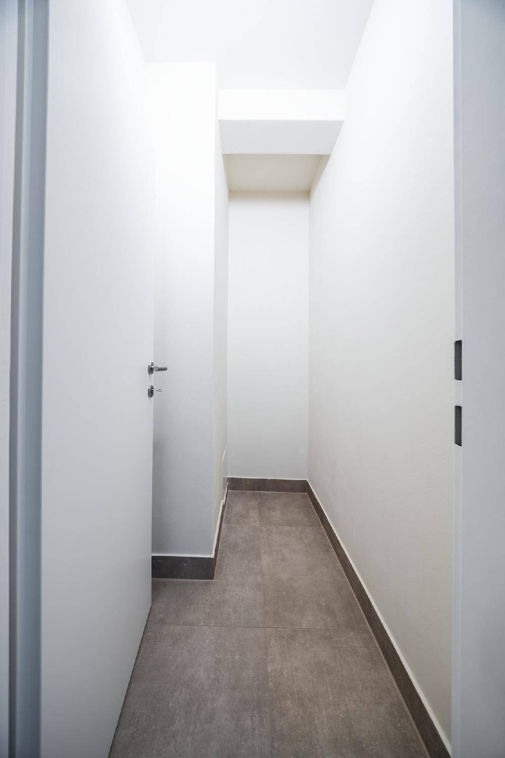 Schmaler, leerer Abstellraum mit Fliesenboden und weißen Wänden, ideal für zusätzlichen Stauraum.