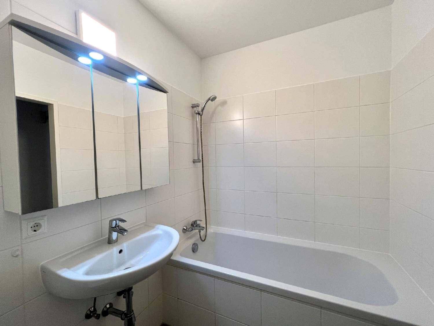 Helles Badezimmer mit Badewanne, Waschbecken und Spiegelschrank, komplett gefliest.