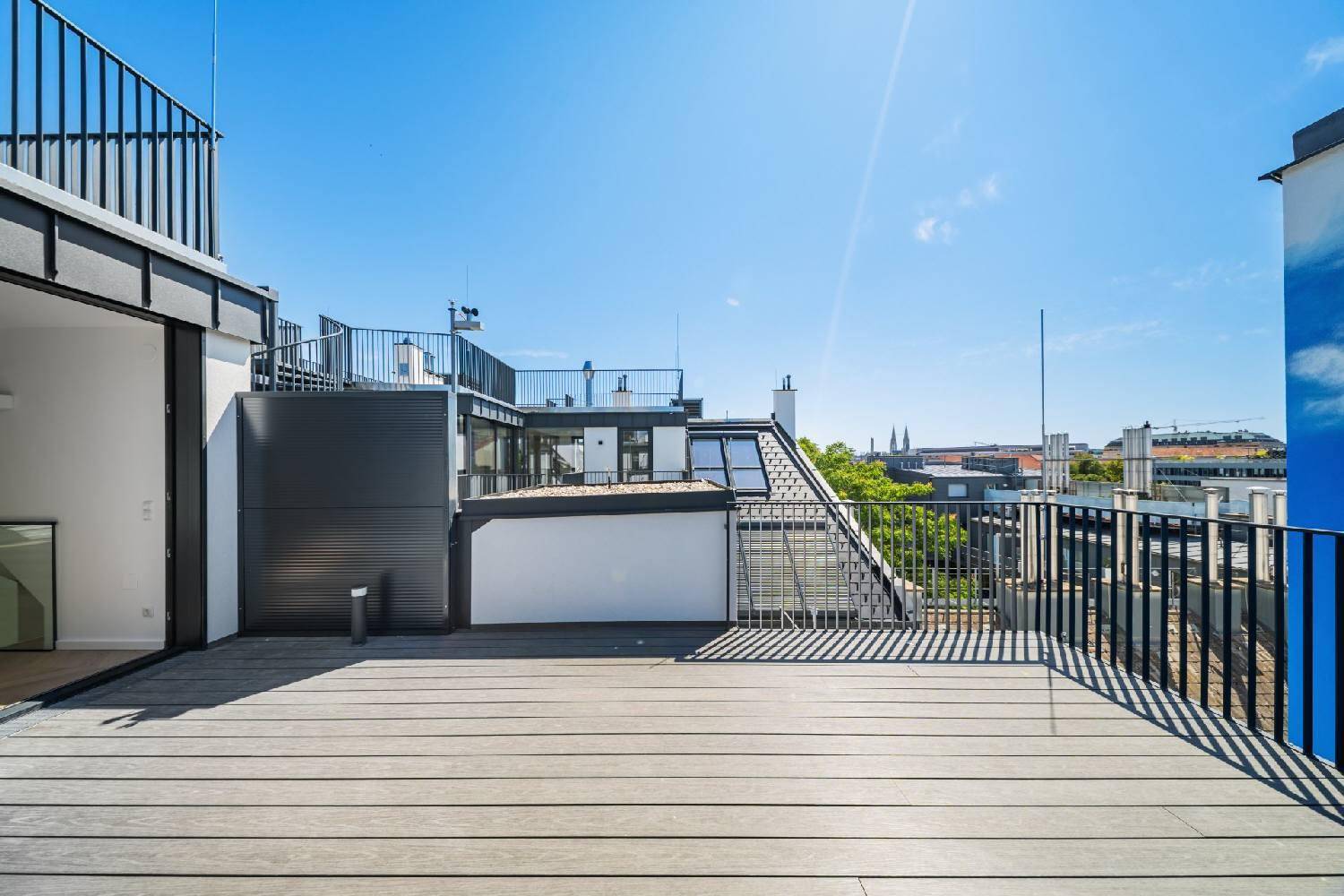 Weitläufige Dachterrasse mit Holzdeck und Panoramablick auf die Stadt und die umliegenden Dächer.