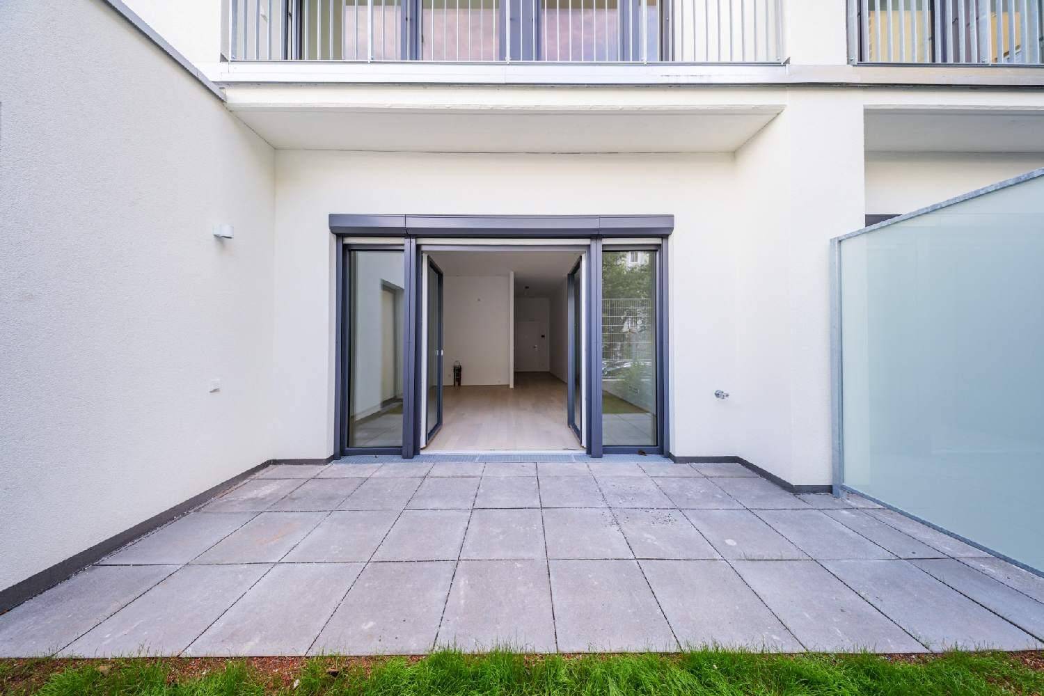 Geräumige, gepflasterte Terrasse mit direktem Zugang zum Innenbereich und Blick auf einen Balkon.