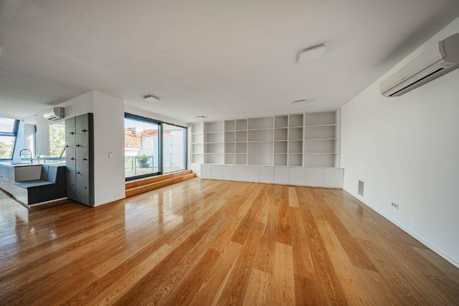 Geräumiger Wohnbereich mit Holzboden, integrierten Regalen und Schiebetüren zur Terrasse.