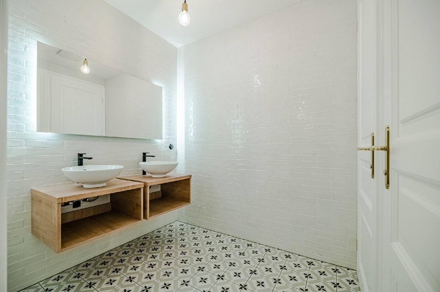 Modernes Badezimmer mit zwei Aufsatzwaschbecken, Holzunterschränken und gemusterten Fliesen.