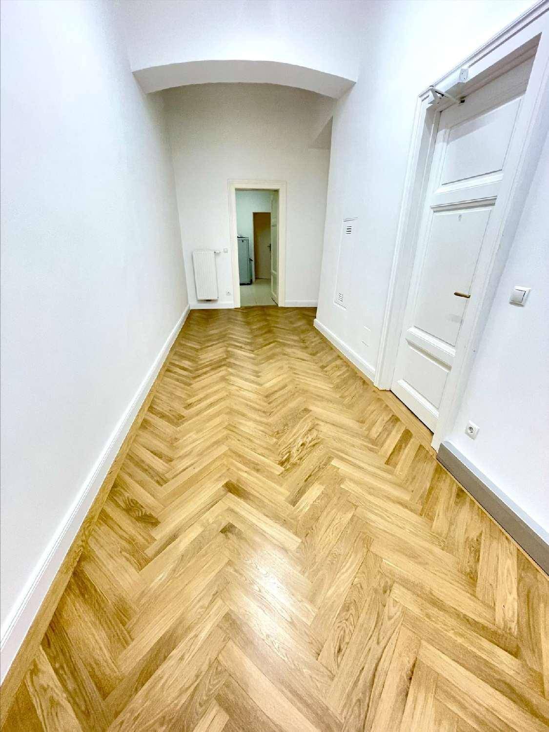 Langer Flur mit Fischgrätparkett und weißen Wänden, der zu weiteren Räumen der Wohnung führt.