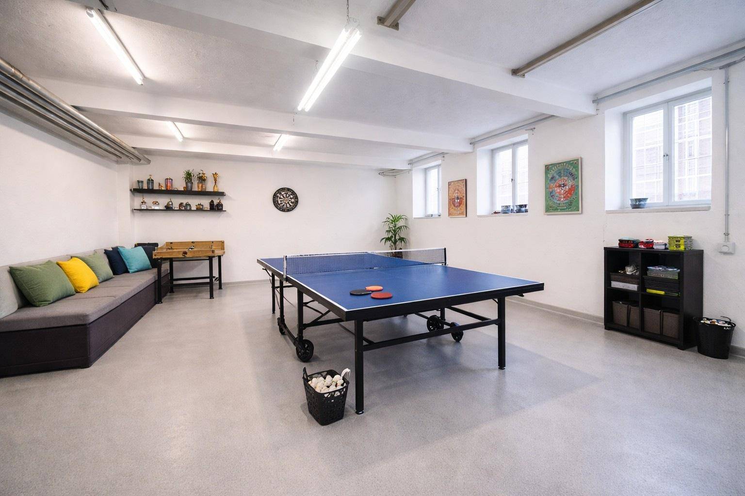Geräumiger Freizeitraum mit Tischtennisplatte, bequemer Sitzgelegenheit und weiteren Unterhaltungsmöglichkeiten.