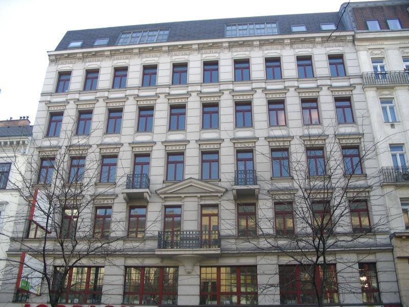 Klassische Fassade eines Mehrfamilienhauses mit vielen Fenstern und kleinen Balkonen.