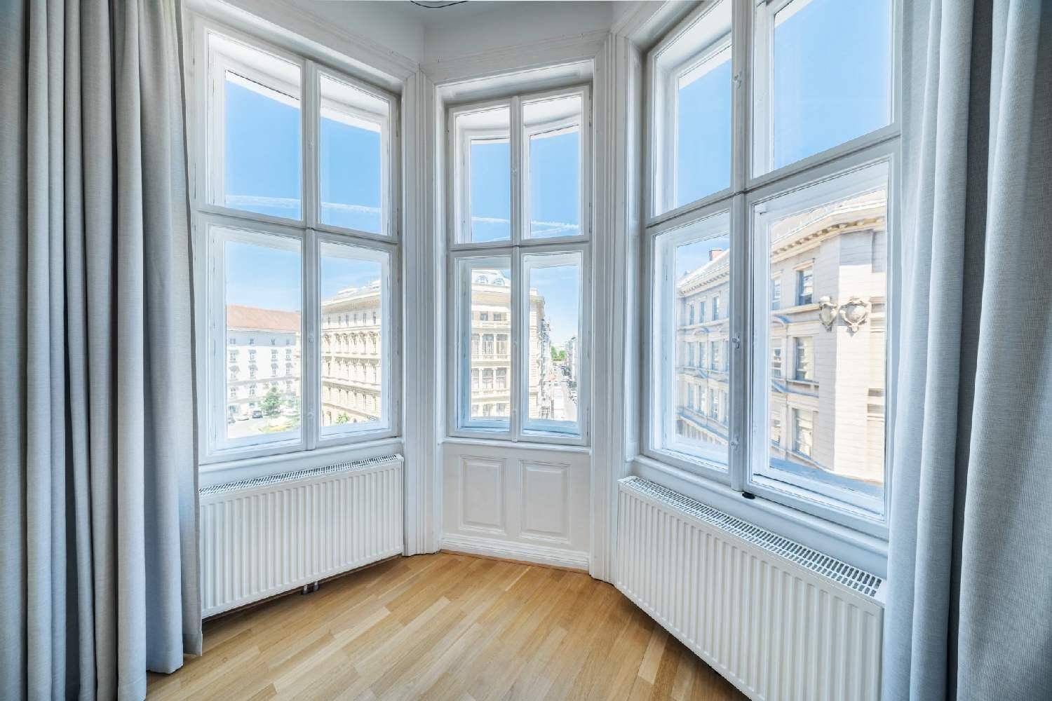 Erkerfenster mit weitem Stadtblick, hohen Decken und Heizkörpern unter den Fenstern.