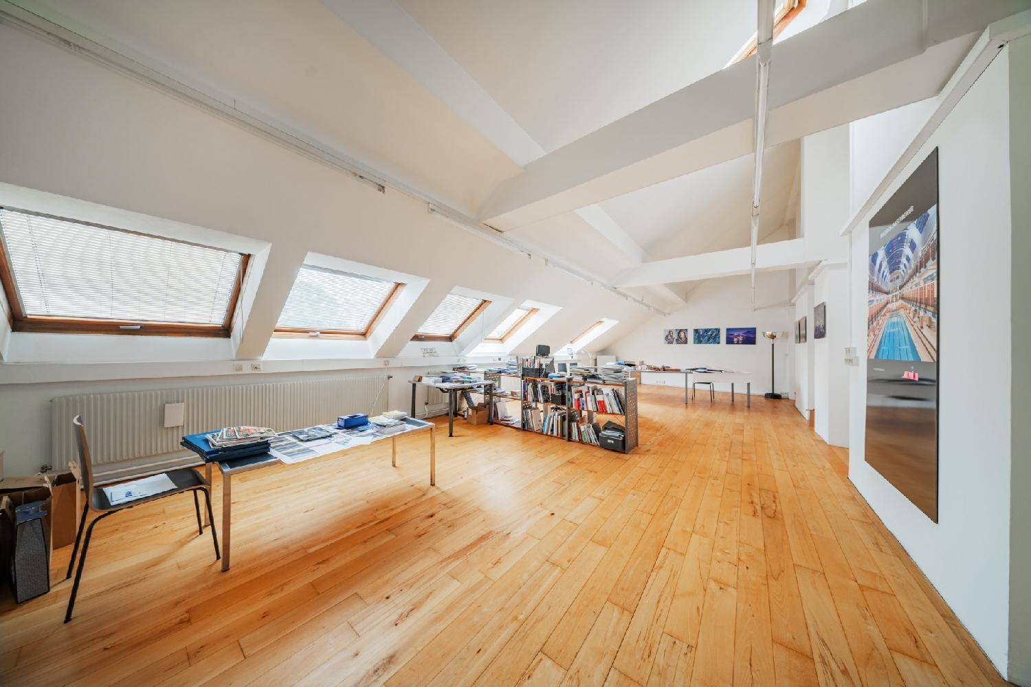 Geräumiges Dachgeschossbüro mit Holzboden, vielen Dachfenstern und offener Gestaltung, ideal für kreative Arbeit.