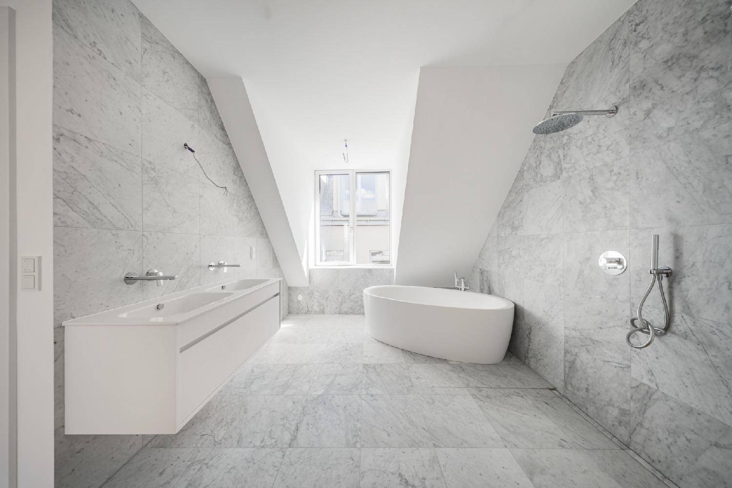 Luxuriöses Badezimmer mit Marmorfliesen, freistehender Badewanne, Doppelwaschbecken und Regendusche.