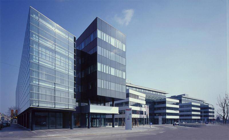 Zeitgenössisches Bürogebäude mit einer Kombination aus Glas- und dunklen Fassadenelementen an einer Straße.
