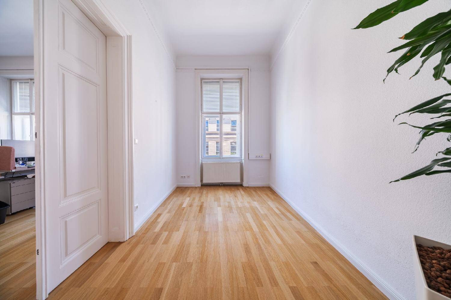 Kleiner Büroraum mit hellem Fischgrätparkett und einem Fenster.