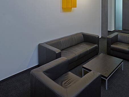 Gemütlicher Wartebereich mit dunklen Ledersofas und einem passenden Couchtisch.