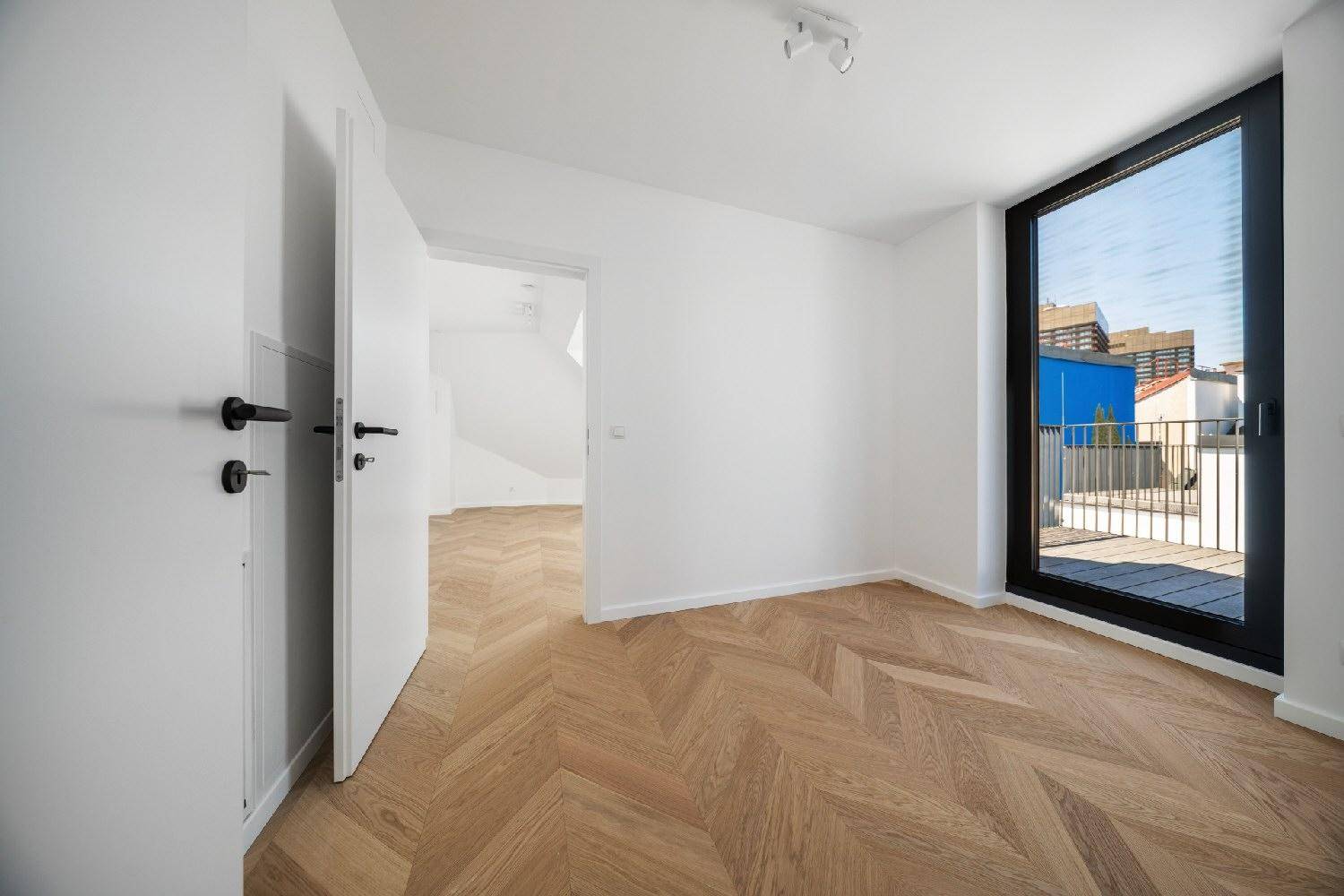 Schlafzimmer mit Fischgrätparkett und direktem Zugang zu einer kleinen, privaten Dachterrasse.