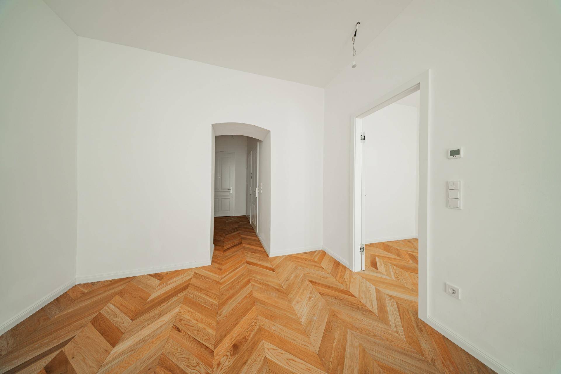 Heller Flur mit Fischgrätparkett und Durchgängen zu weiteren Zimmern, frisch renoviert.