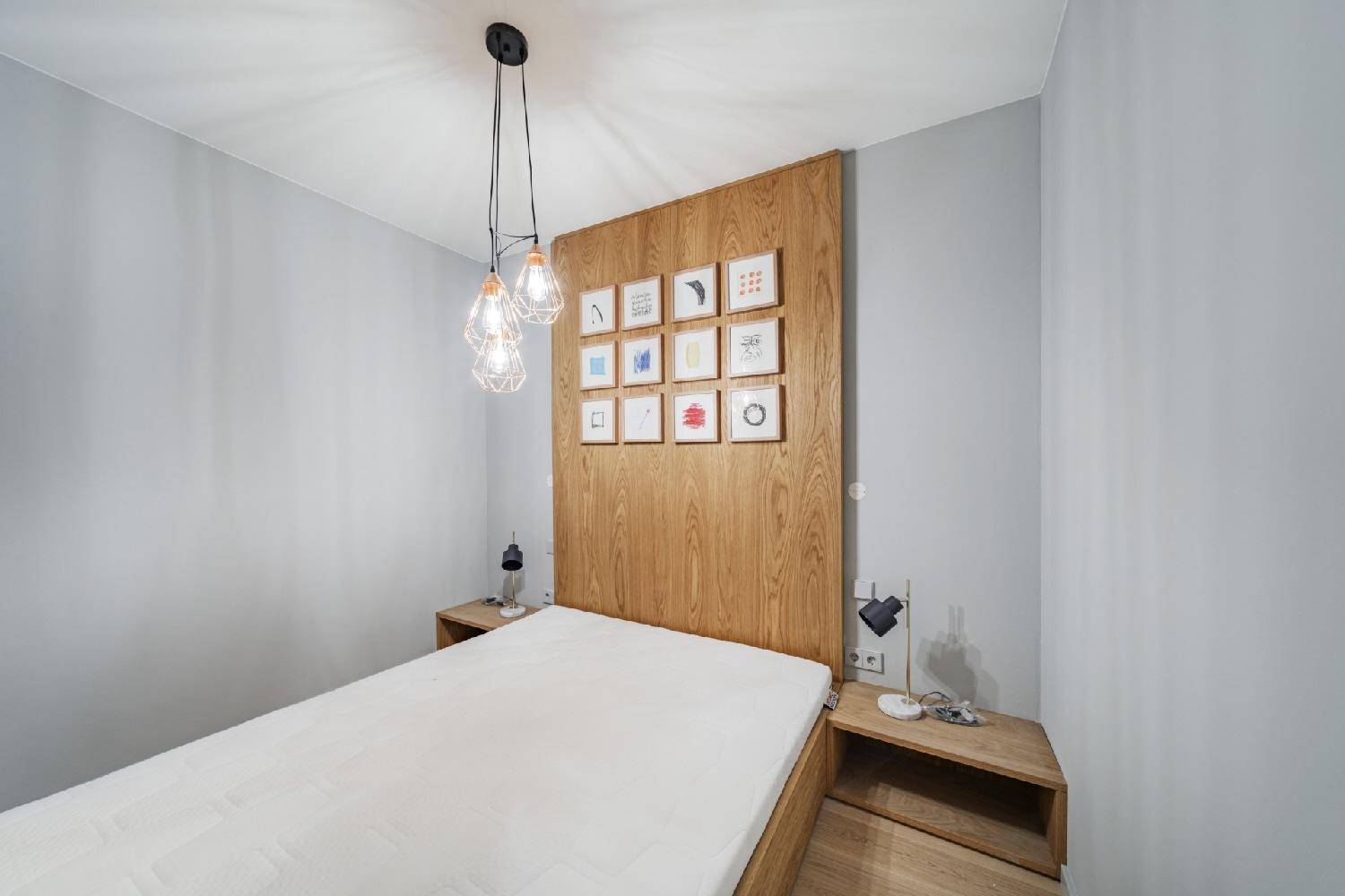 Schlafzimmer mit Holzkopfteil, minimalistischer Einrichtung und indirekter Beleuchtung.