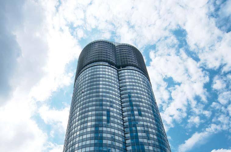 Moderner Wolkenkratzer mit einer beeindruckenden Glasfassade unter blauem Himmel mit Wolken.