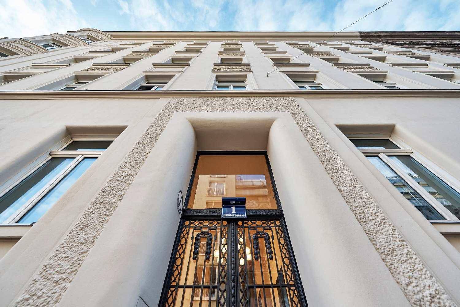 Detailansicht des Haupteingangs mit kunstvollem schmiedeeisernem Tor und Hausnummer.