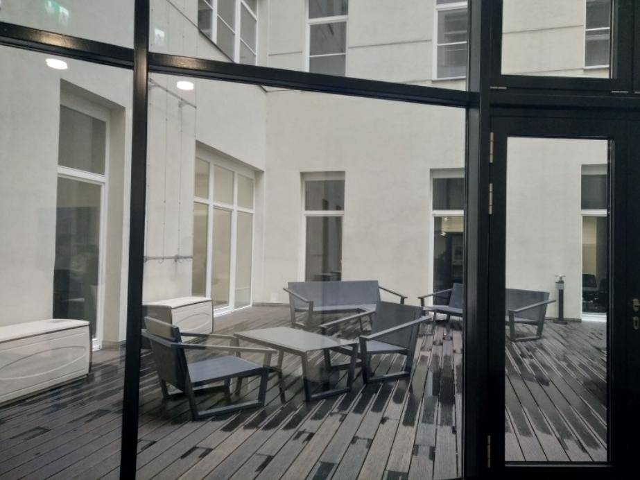 Ruhiger Innenhof mit Holzterrasse und modernen Sitzgelegenheiten, perfekt für entspannte Pausen im Freien.
