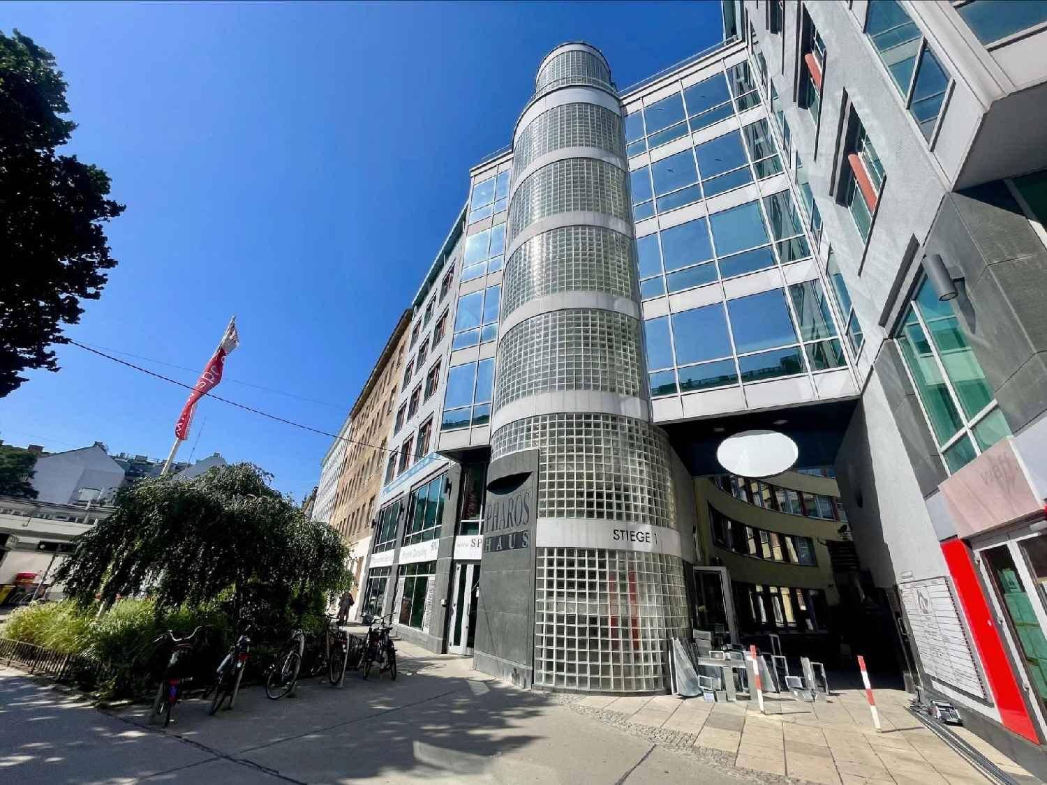 Moderne Bürogebäude-Fassade mit markanter Glasbaustein-Rundung und großen Fensterflächen an einem sonnigen Tag.
