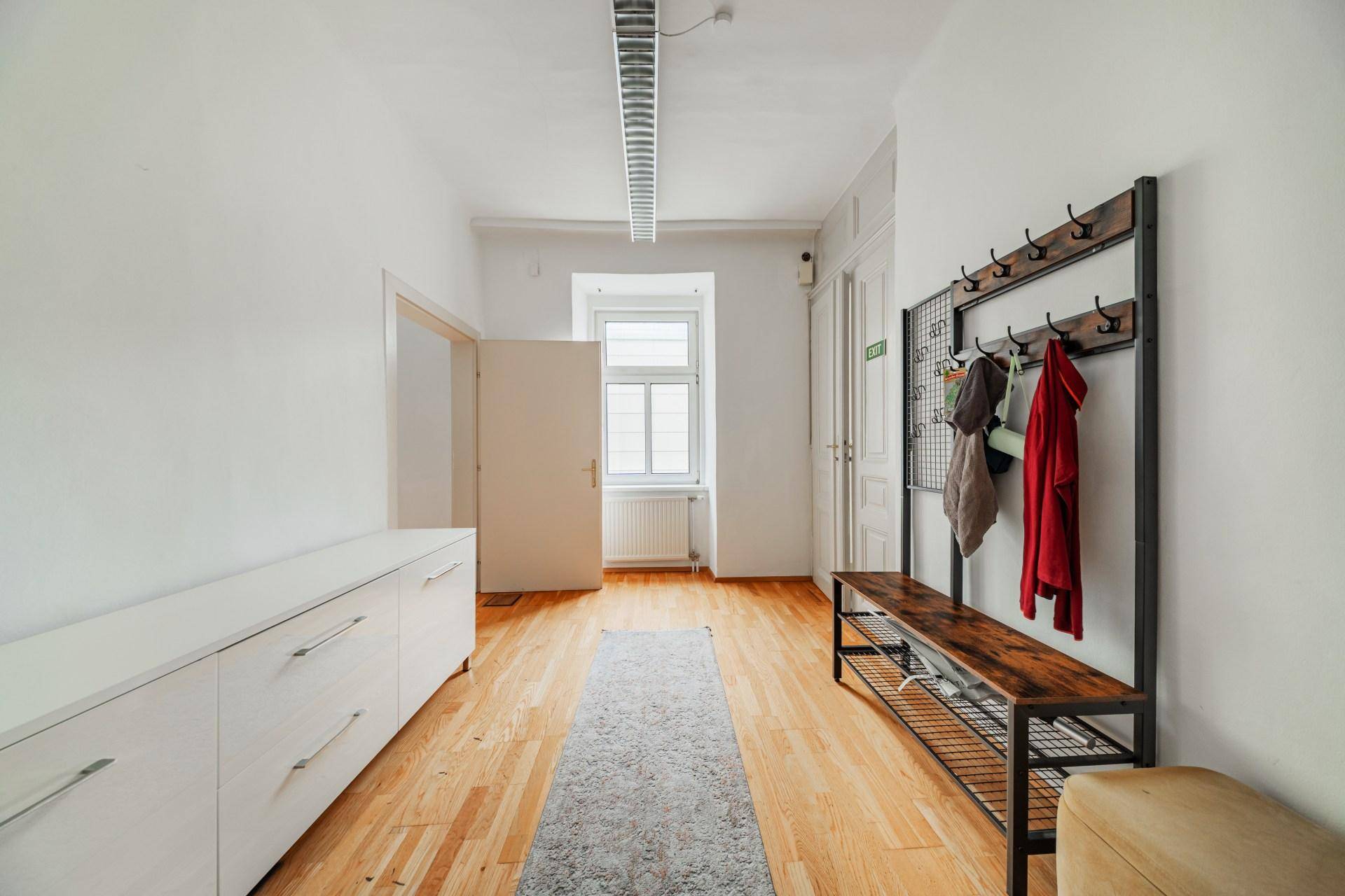 Langer Flur mit Holzboden, weißer Kommode und einer modernen Garderobe.