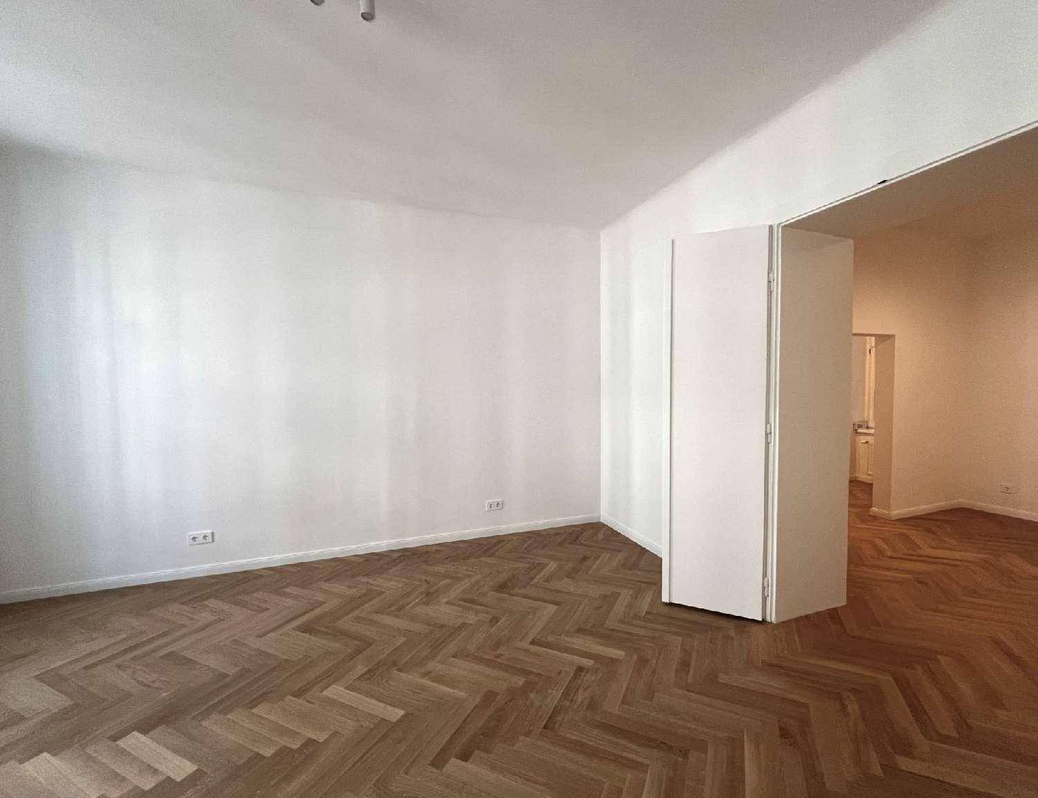 Großes, helles Zimmer mit Fischgrätparkett und einem breiten Durchgang zu angrenzenden Räumen.