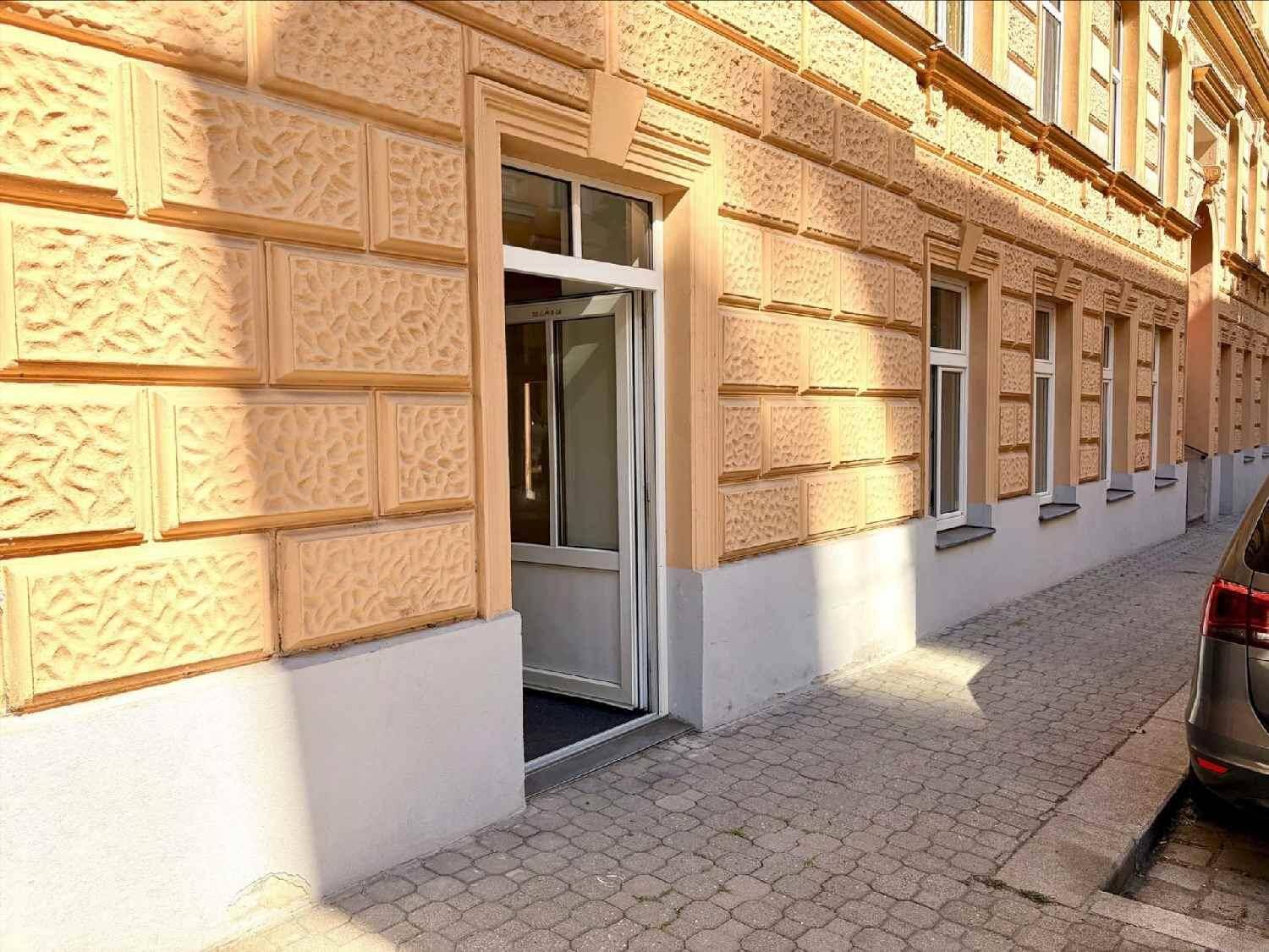 Außenansicht des Gebäudes mit strukturierter Fassade und dem Eingangsbereich auf Straßenniveau.