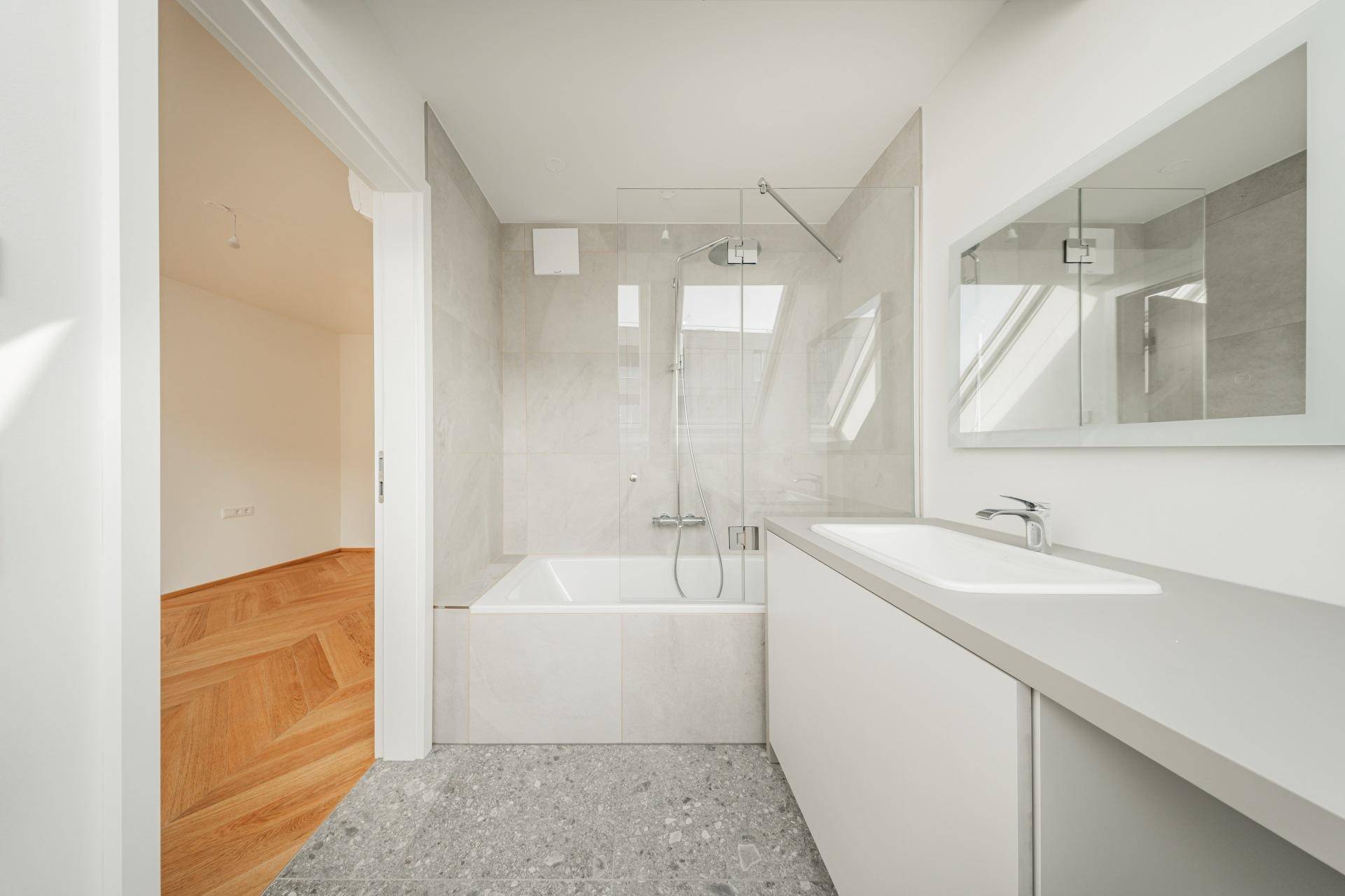 Modernes Badezimmer mit Badewanne, Dusche, Einzelwaschbecken und großformatigen Fliesen.