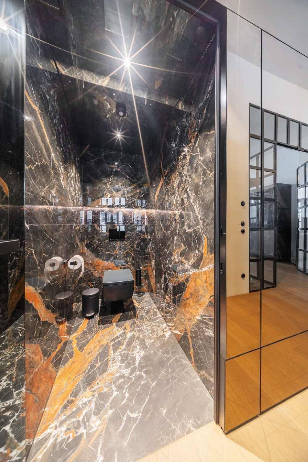Elegante Gästetoilette, vollständig mit schwarzem Marmor verkleidet, mit modernem WC und Spiegel.