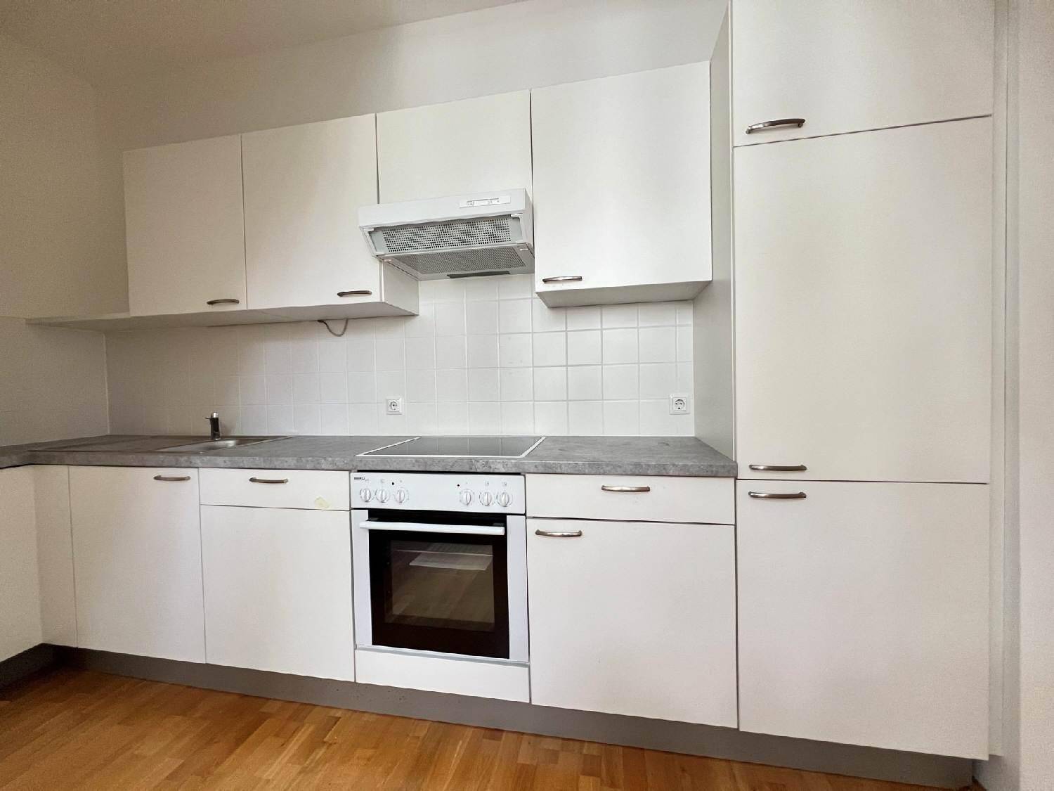 Funktionale Küche mit weißen Schränken, integriertem Backofen und Dunstabzugshaube.